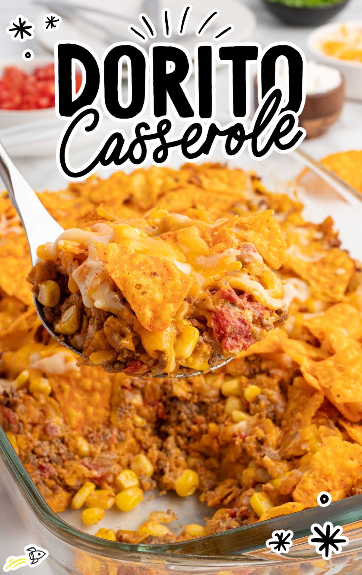 Dorito casserole served on a white plate and topped with sour cream, diced tomatoes, and green onions.