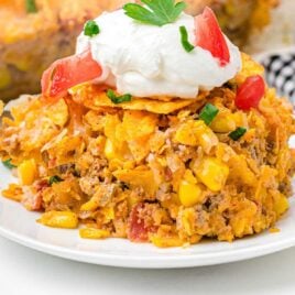 close up shot of a plate of Dorito Casserole topped with sour cream and tomatoes
