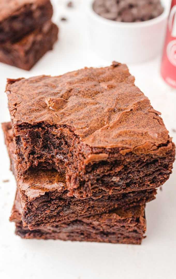 close up shot of Dr Pepper Brownies stacked on top of each other with a bite taken out of the top brownie