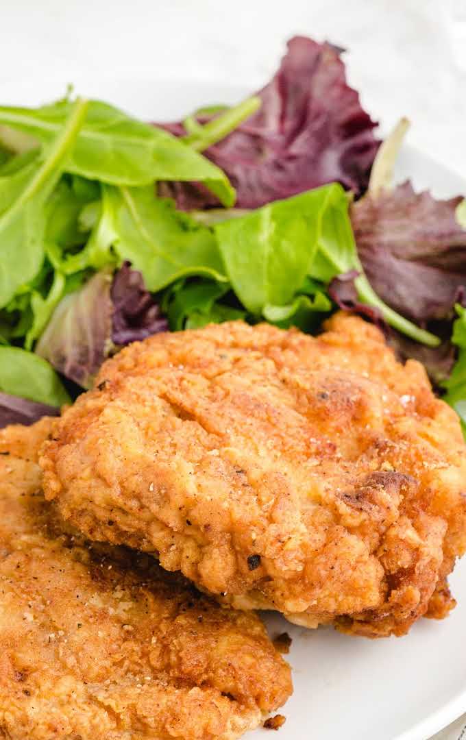 close up shot of Fried Pork Chops on a plate with a side of salad