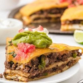side shot of Taco Pie topped with guacamole, cream cheese, and salsa on a plate