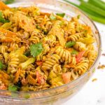 close up shot of taco pasta salad garnished with cilantro in a clear bowl