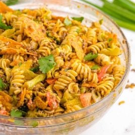 close up shot of taco pasta salad garnished with cilantro in a clear bowl
