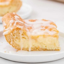 side shot of cheese danish with glaze on a white plate