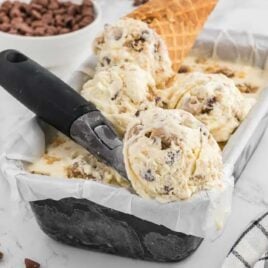 close up shot of Cookie Dough Ice Cream in a pan with some being scooped out with a ice cream scooped