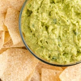 close up overhead shot of guacamole in a clear bowl with chips