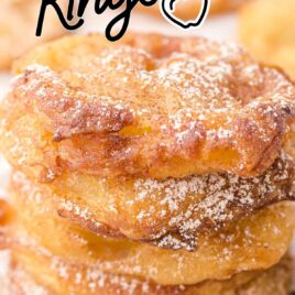 apple fritter rings stacked on top of each other and drizzled with powder sugar