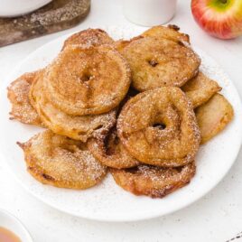 close up shot of Apple Fritter Rings stacked on top each other on a plate