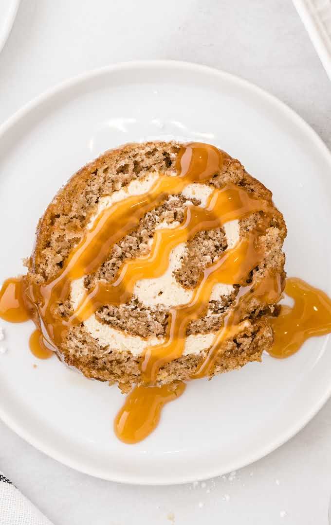 overhead shot of a slice of caramel banana cake roll drizzled with caramel sauce on a plate