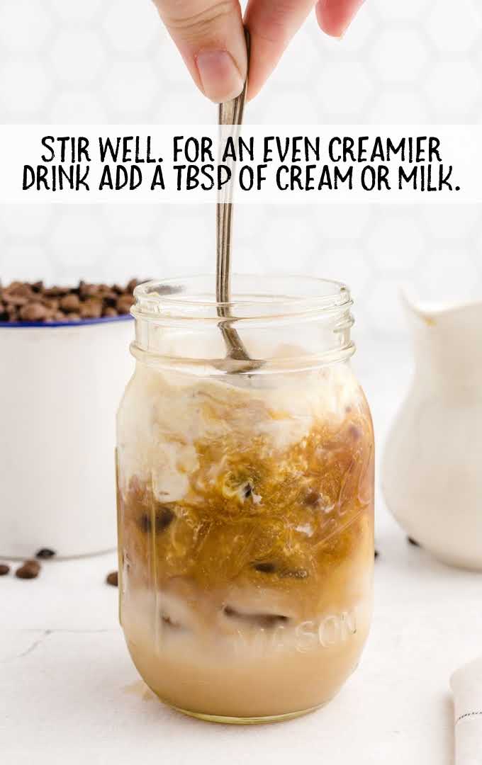 Iced Caramel Macchiato process shot of drink in a glass jar being stirred with a spoon