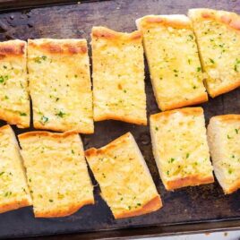close up shot of slices of garlic bread on a wooden board