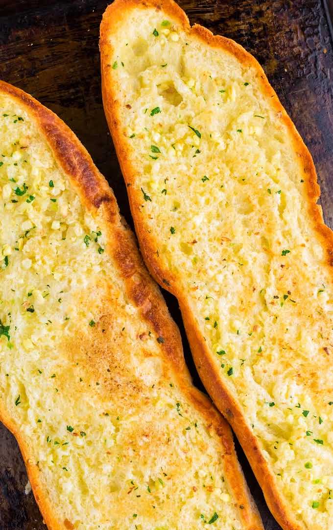 close up shot of two loaves of garlic bread on a tin pan