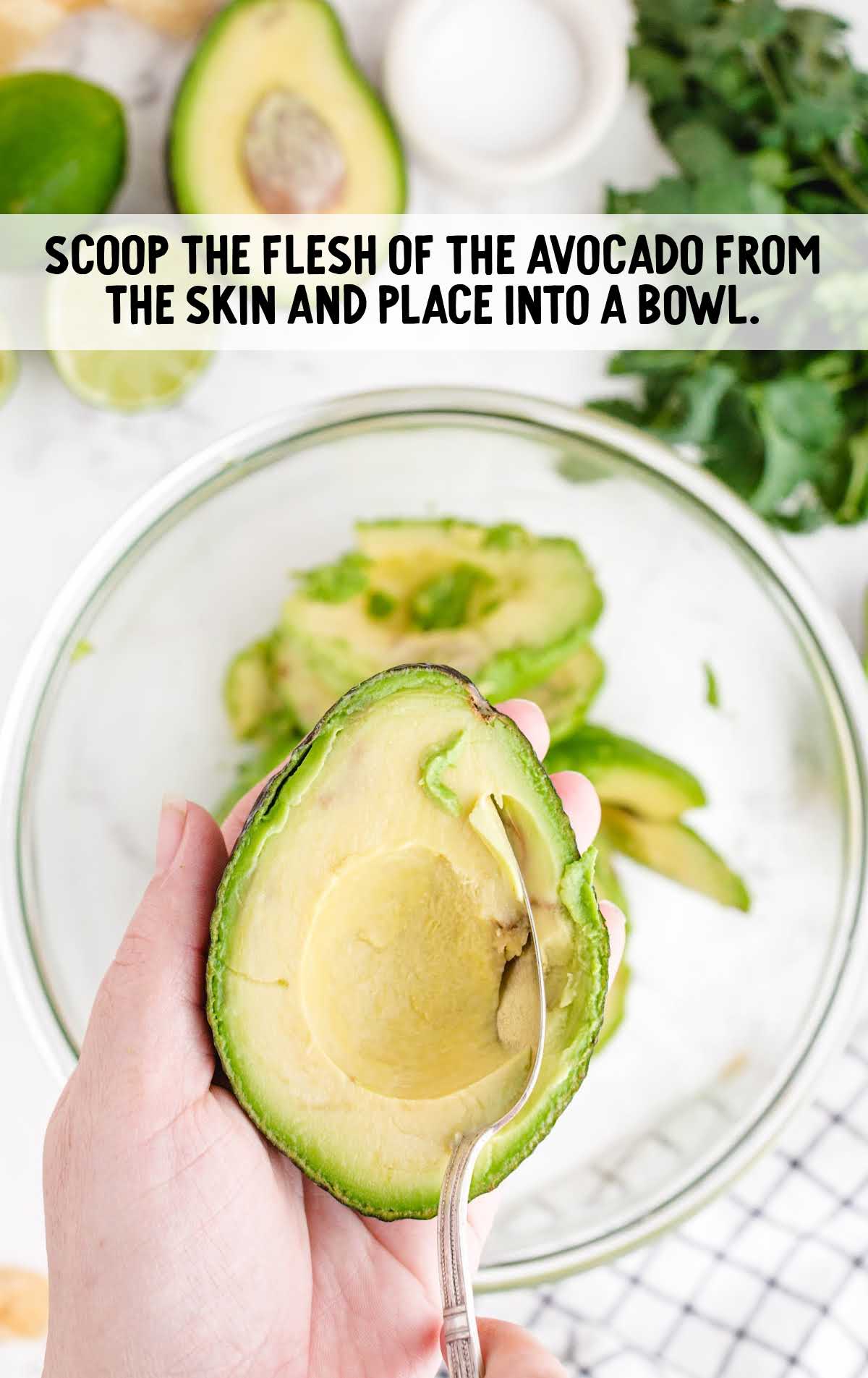 flesh being scooped out of avocado and placed into bowl