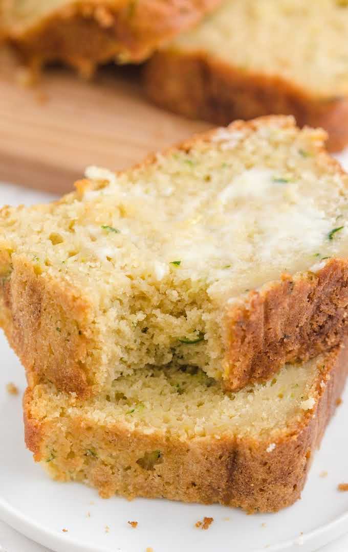 close up shot of slices of zucchini bread spread with butter on a plate