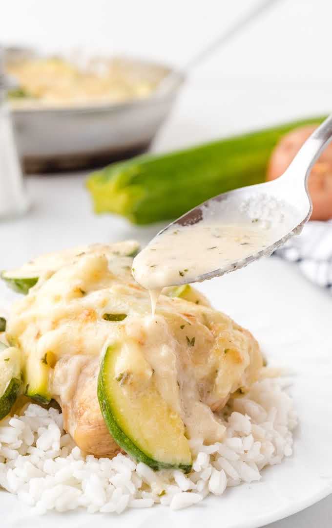 zucchini gratin served over white rice and drizzled with sauce on a plate