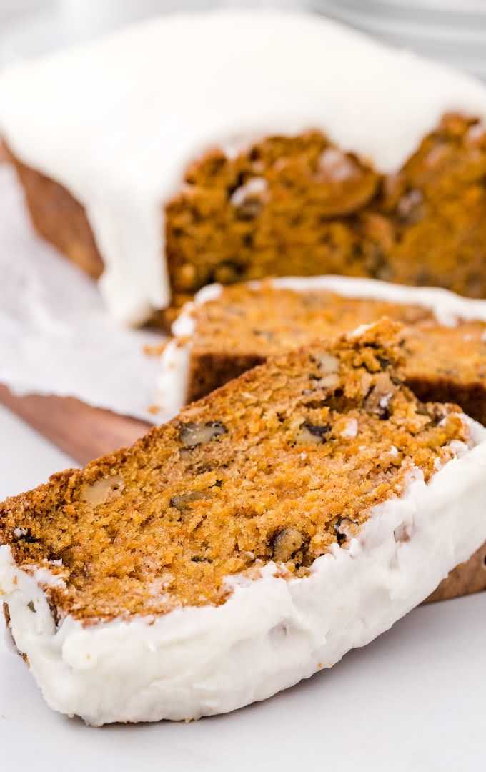 close up shot of a loaf of carrot bread sliced on a wooden tray