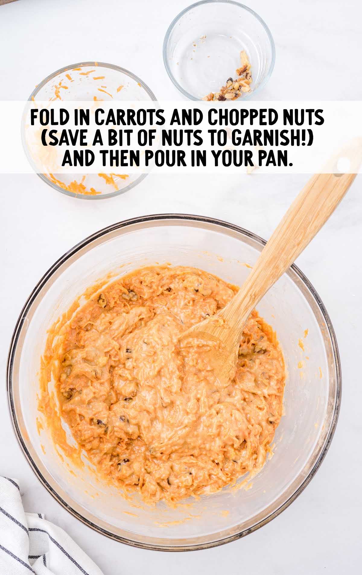 carrots and chopped nuts being mixed in a bowl with a large spoon