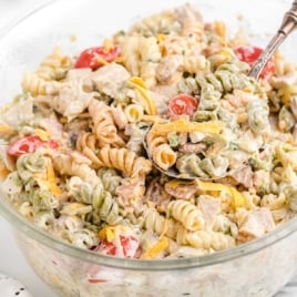 Glass bowl filled with mixed chicken bacon ranch pasta salad showing tri-color pasta and creamy texture.
