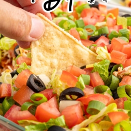 a baking dish of 7 Layer Dip with a tortilla chip