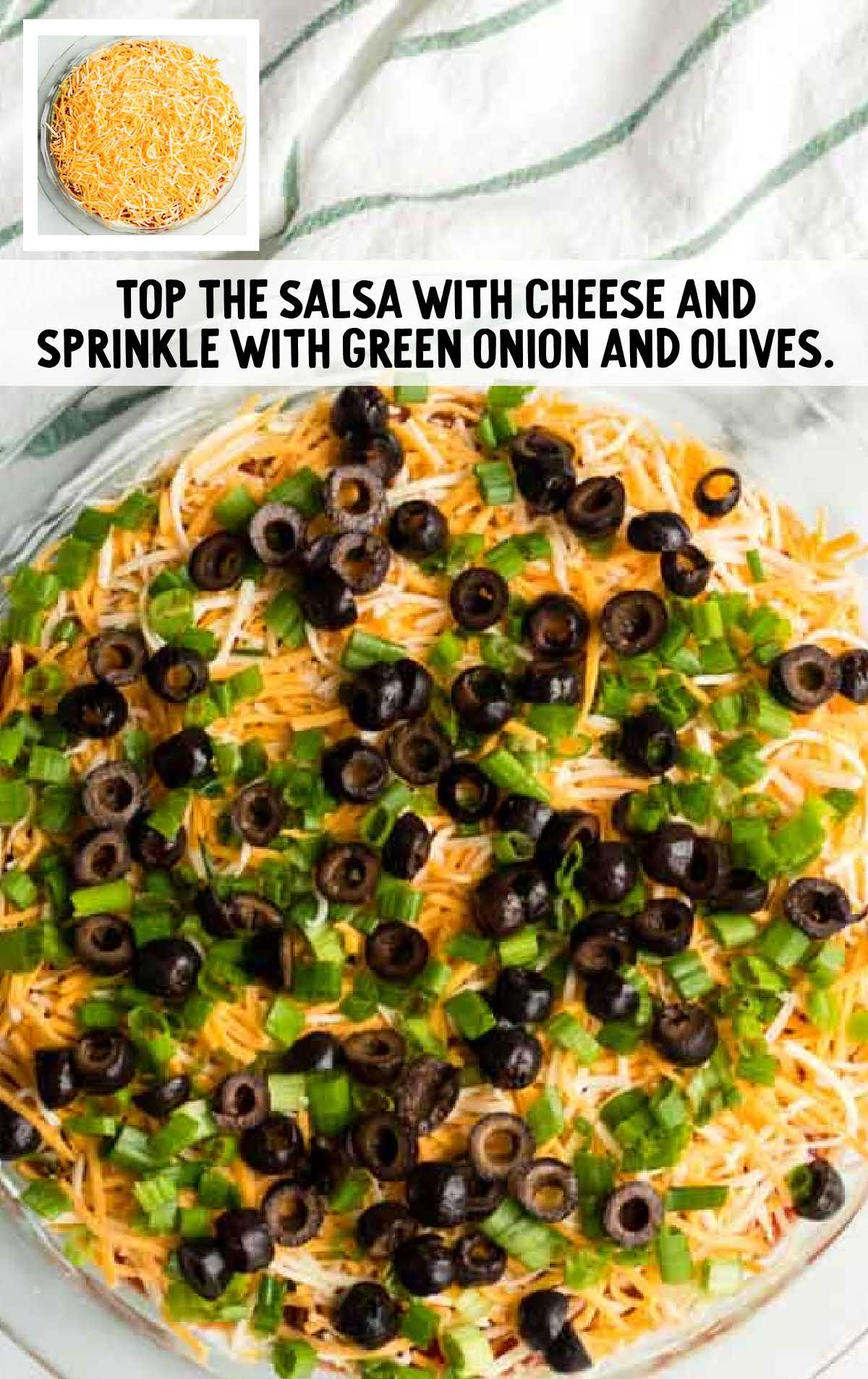 seven layer dip process shot of cheese, green onions, and olives placed on top of ingredients in a dish
