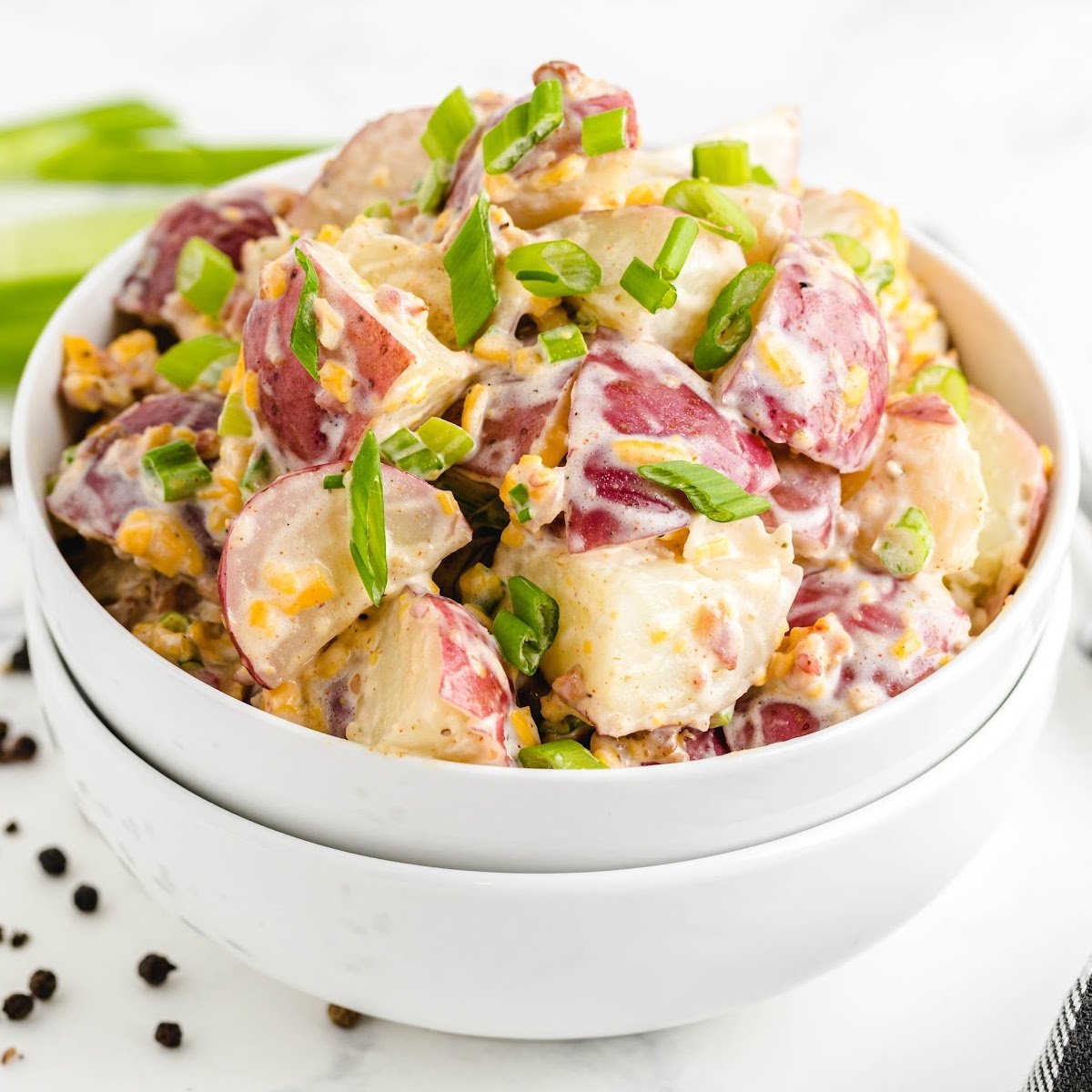 close up shot of a bowl of ranch potato salad drizzled with ranch dressing and garnished with green onions