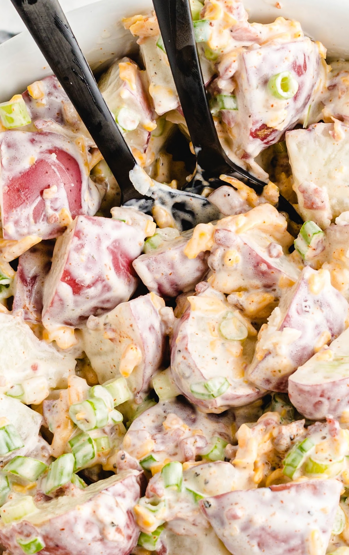 close up overhead shot of ranch potato salad drizzled with ranch dressing and garnished with green onions