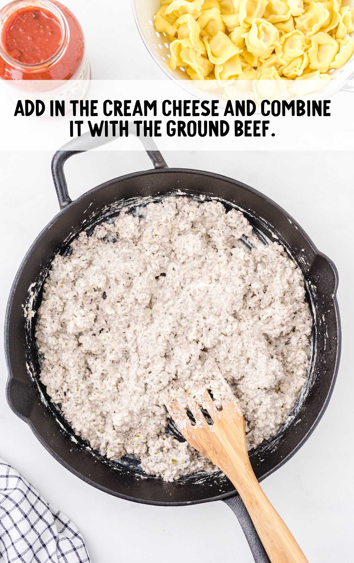 cream cheese being added to ground beef in a skillet
