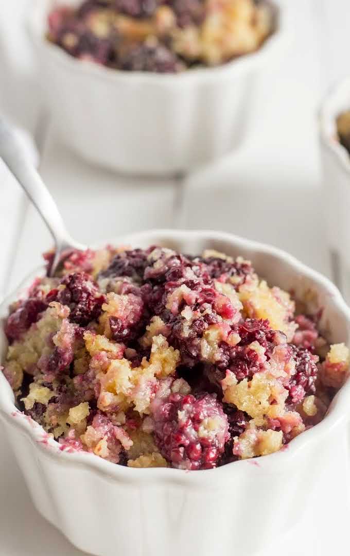 close up shot of a serving of blackberry cobbler in a white bowl