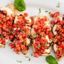 Bruschetta Chicken topped with basil on a serving tray