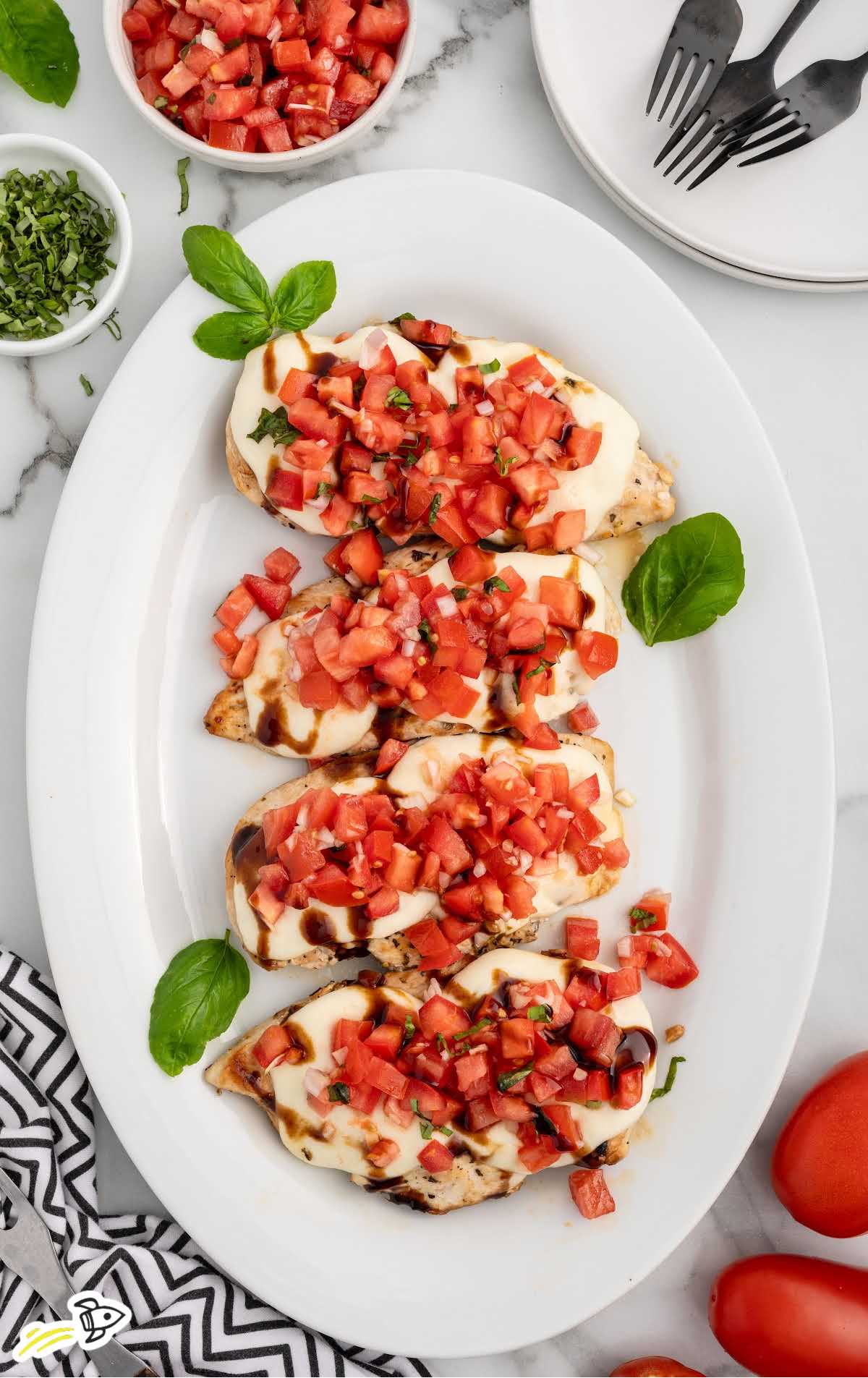 Bruschetta Chicken topped with basil on a serving tray