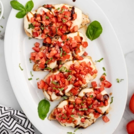 Bruschetta Chicken topped with basil on a serving tray