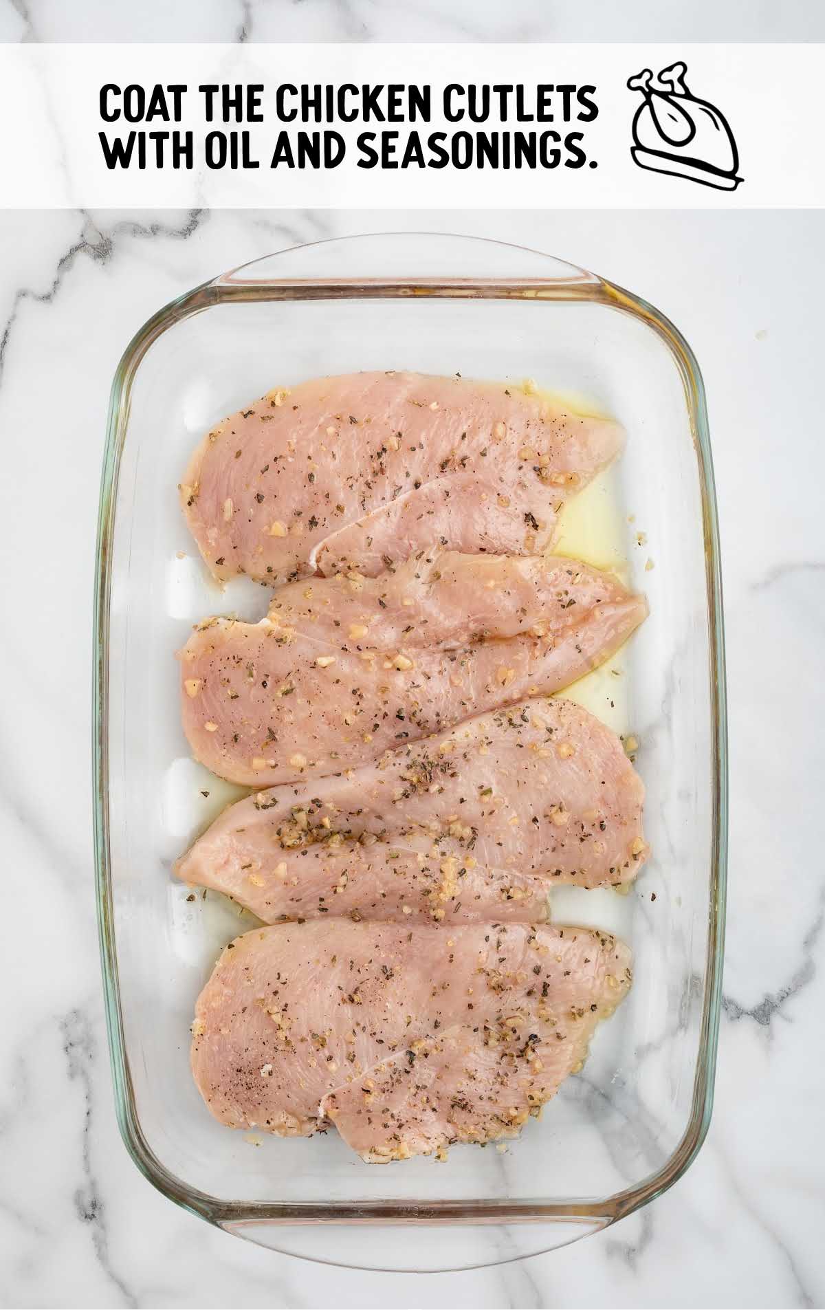 chicken cutlets topped with oil and seasonings in a baking dish