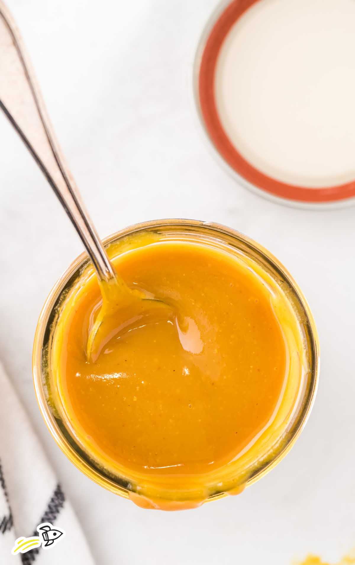 close up overhead shot of Carolina mustard BBQ sauce in a mason jar with a spoon