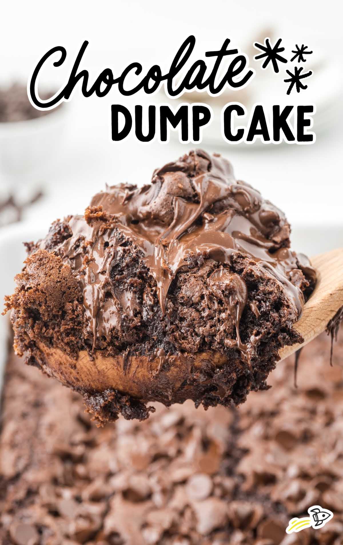 A wooden spoon lifts a gooey, chocolate dump cake topped with melted chocolate from a baking dish. The text Chocolate Dump Cake Recipe is written above the cake.