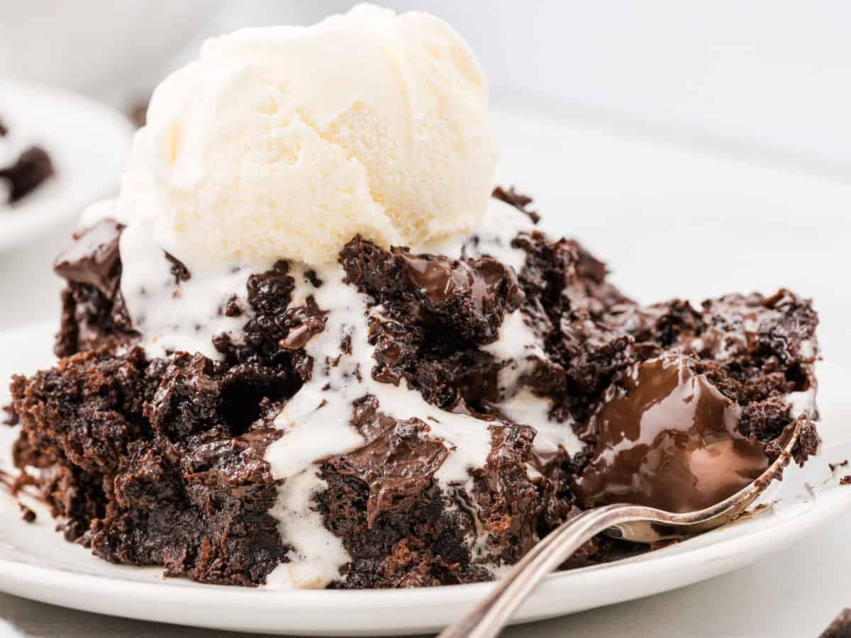 Chocolate lava cake inspired by the classic Chocolate Dump Cake recipe, with melted chocolate and a scoop of vanilla ice cream on top, served on a white plate with a spoon.