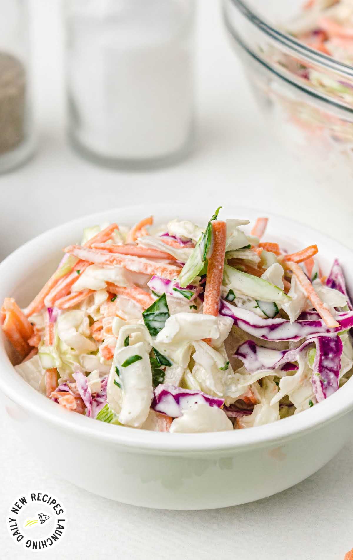 classic coleslaw topped with homemade salad dressing in a large bowl with wooden spoons