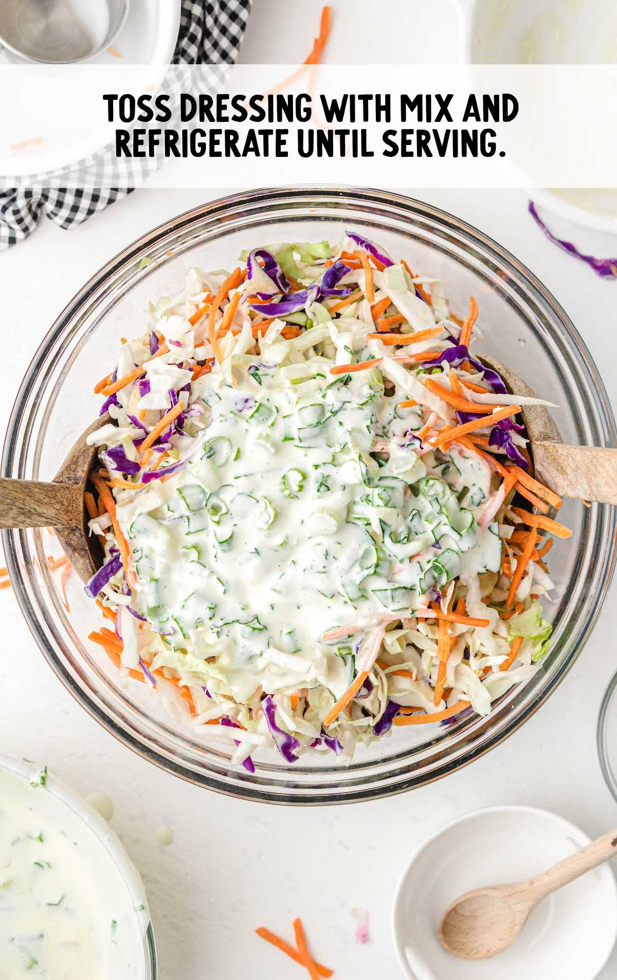 salad dressing being poured and tossed into the coleslaw mixture
