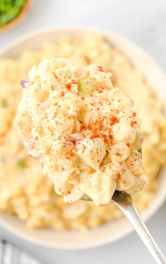 lose up shot of egg pasta salad on a spoon over egg pasta salad in a bowl