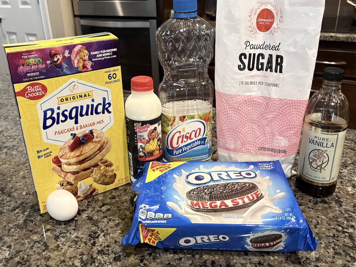 A countertop set for Deep Fried Oreos with Bisquick pancake mix, an egg, Crisco vegetable oil, heavy whipping cream, powdered sugar, pure vanilla extract, and a package of Oreo Mega Stuf cookies.