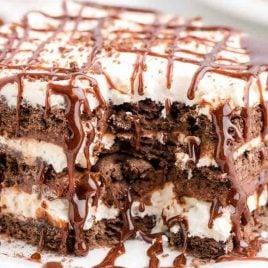 close up shot of icebox cake drizzled with chocolate syrup on a white plate