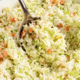 Spoonful of homemade KFC copycat coleslaw being lifted from a white bowl with text “How to Make KFC Copycat Coleslaw – That’s Just Like the Original.”
