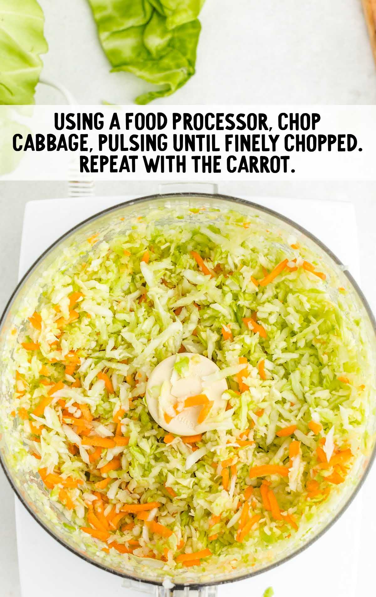 Food processor bowl filled with finely chopped cabbage and carrots for homemade coleslaw.