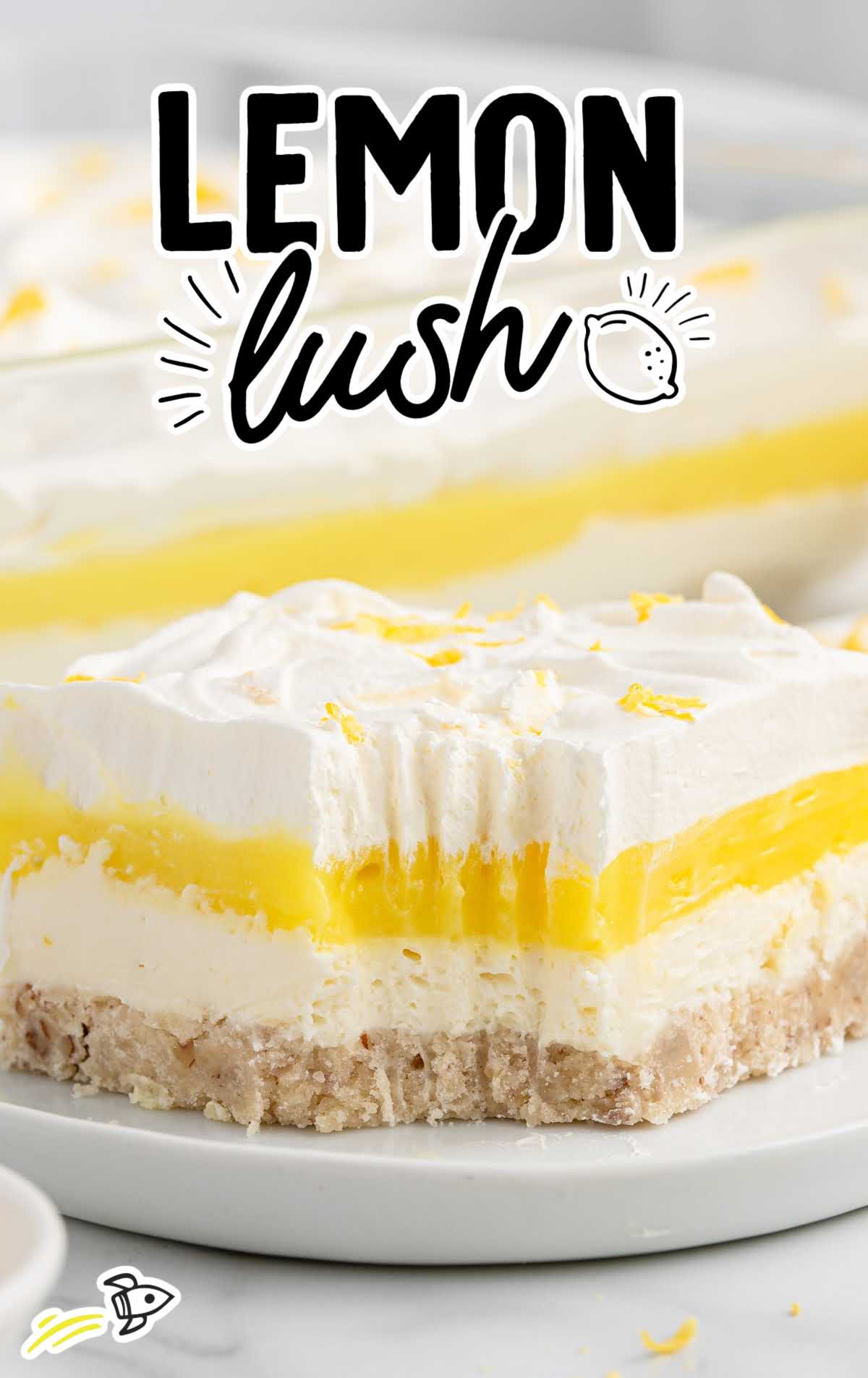 Close-up of a slice of lemon lush showing distinct creamy cheesecake and lemon pudding layers on a pecan crust.