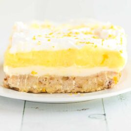 a close up shot of a slice of lemon lush on a white plate