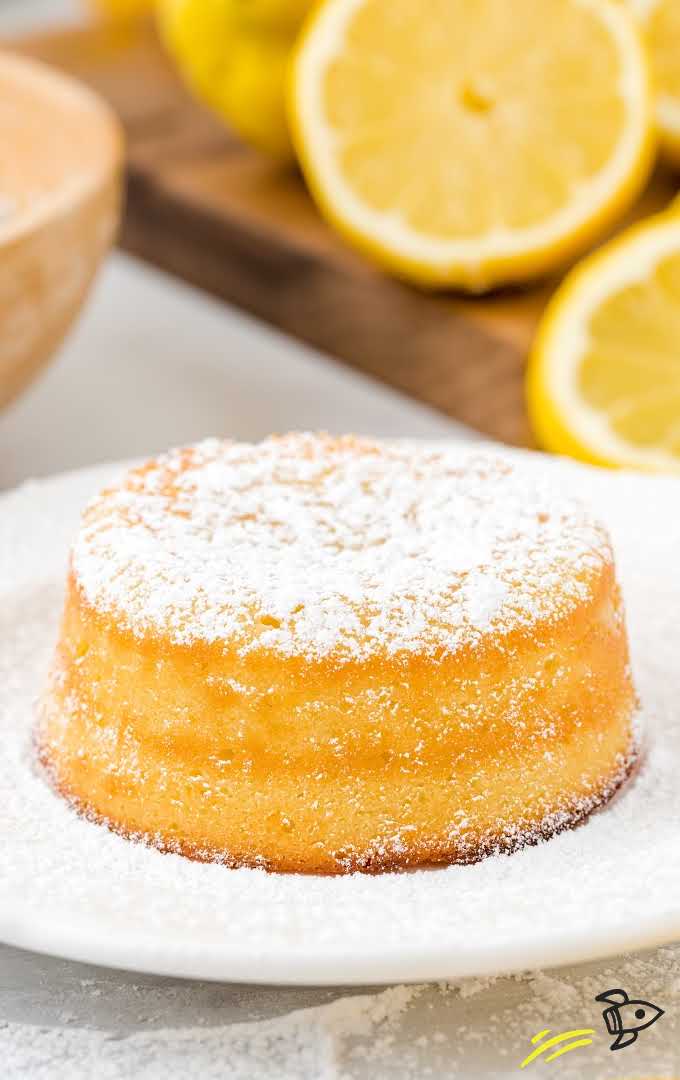 close up shot of lemon lava cake dusted with powdered sugar on a white plate
