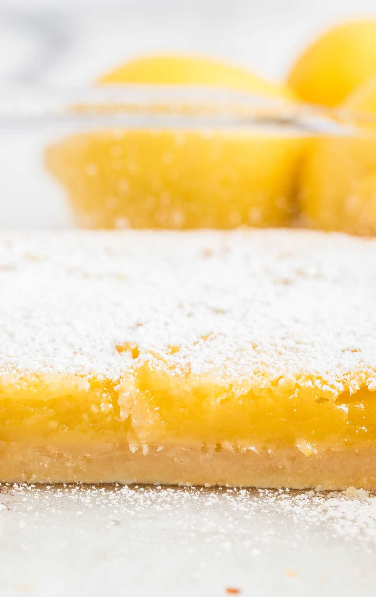 a close up shot of Lemon Bars dusted with powdered sugar