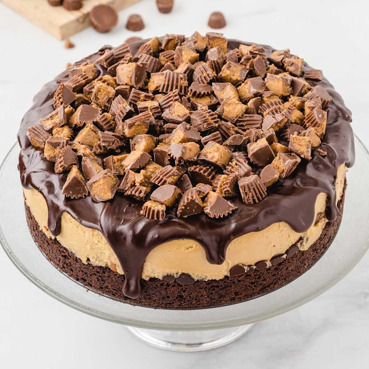 Overhead shot of the whole Reese’s cheesecake on a cake stand, topped with chopped peanut butter cups.