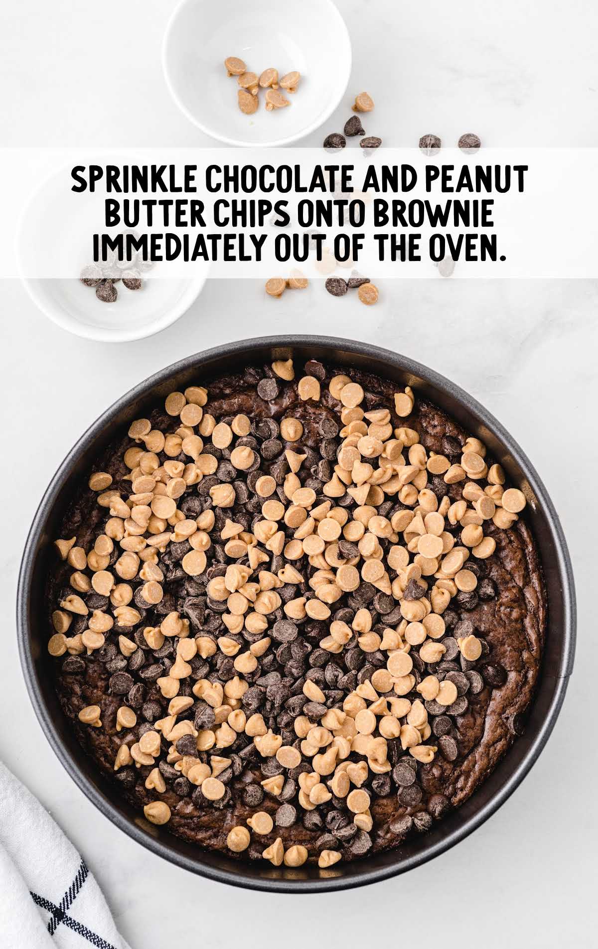 Baked brownie layer topped with chocolate and peanut butter chips, shown right after coming out of the oven.