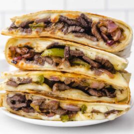 close up shot of steak quesadilla recipe stacked on top of each other on a plate