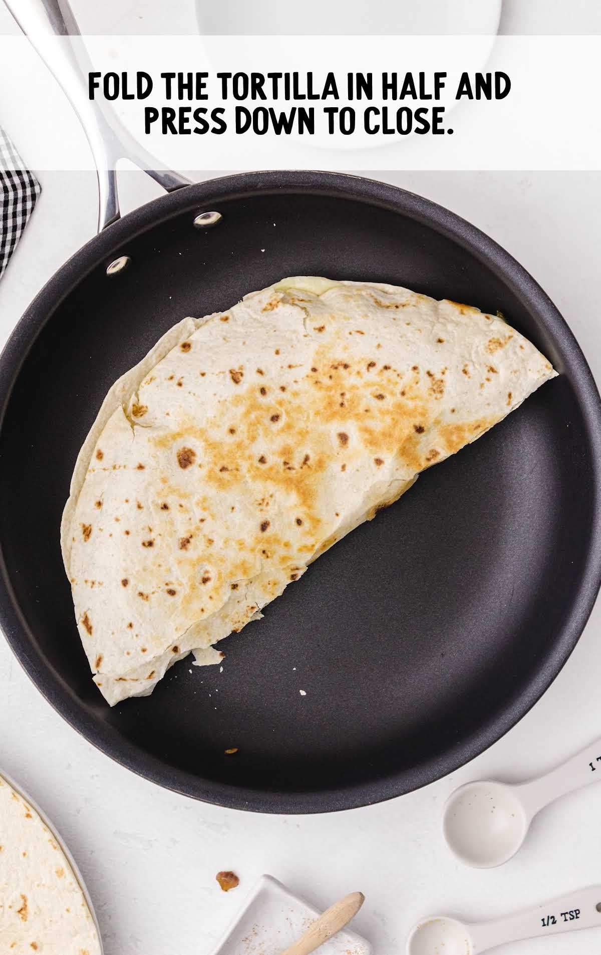 quesadilla being assembled in a skillet